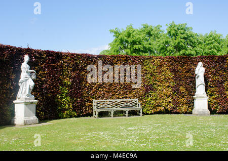 Panchina incorniciata da statue in English Country Garden Foto Stock