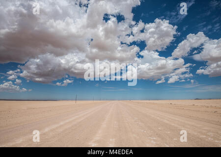 Immagine vibrante della strada nel deserto e blu cielo nuvoloso Foto Stock