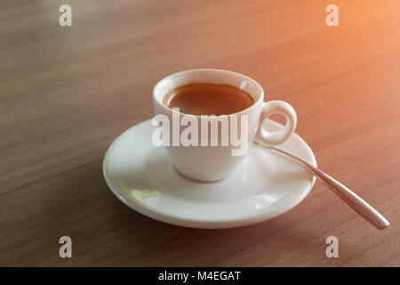 Caffè Espresso tazza bianca sul tavolo con illuminazione arancio. Foto Stock