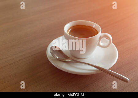 Caffè Espresso tazza bianca sul tavolo con illuminazione arancio. Foto Stock