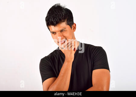 Giovane uomo in abbigliamento casual con mano sul mento di Pune, Maharashtra. Foto Stock