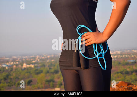 Athletic donna esercita con corda da salto con sfondo di montagne di Pune, Maharashtra. Foto Stock