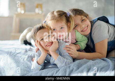 Due sorelle e un fratello. Tre bambini della stessa famiglia sono sdraiato sul letto. Foto Stock
