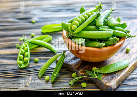 Baccelli di piselli dolci in una ciotola di legno. Foto Stock