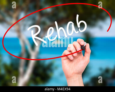 Man mano che scrive Rehab con pennarello nero su schermo visivo Foto Stock