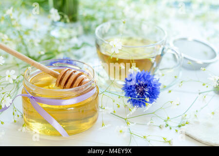 Il miele in vasetti di vetro e la tazza di tè Foto Stock