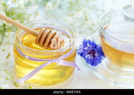 Il miele in vasetti di vetro e la tazza di tè Foto Stock