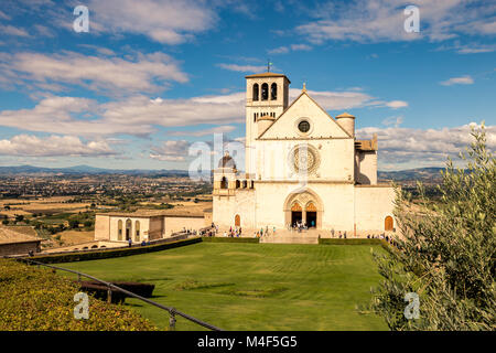 San Francesco di Assisi Chiesa con la statua di San Francesco su un cavallo in primo piano. San Francesco è il santo patrono d'Italia. Il campanile è in grado di Foto Stock