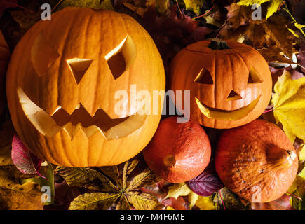 Zucche di Halloween, scolpiti jack-o-lantern in foglie di autunno Foto Stock