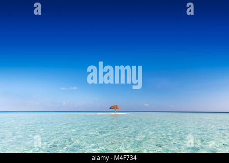 Sandbank tropicale isola con ombrellone. Oceano Indiano, Maldive. Foto Stock