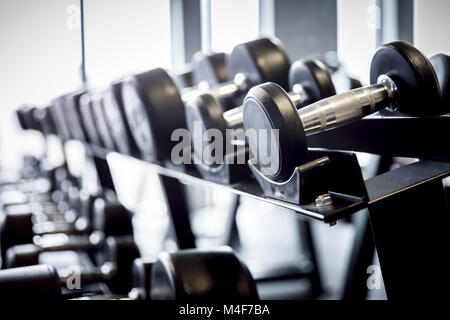 Righe di pesi su un rack in palestra. Foto Stock