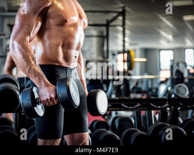Giovane uomo muscolare che lavora fuori in una palestra a. Foto Stock