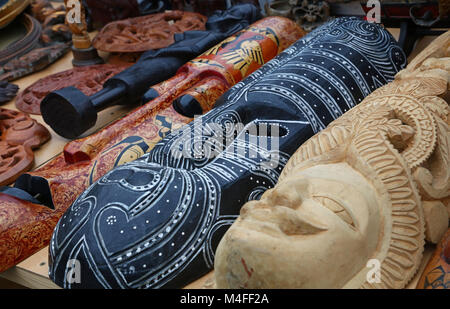 Close up Indiani e Africani fatti a mano in legno etnica maschere intagliate sul mercato al dettaglio, display a basso angolo di visione Foto Stock