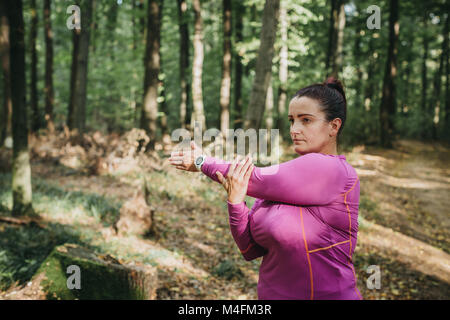 Ritratto di un pareggiatore femmina tenetevi pronti per un jog e facendo alcuni tratti in una foresta. Foto Stock