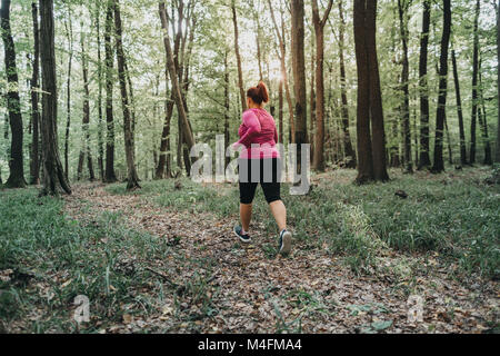 Vista posteriore di una donna sovrappeso cercando di mantenersi in forma e fare jogging. Foto Stock