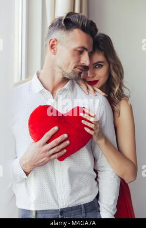Ritratto di abbracciando piuttosto giovane azienda giocattolo di peluche cuore a casa il giorno di san valentino Foto Stock