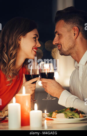 Giovani sorridendo gli amanti della bella guardando ogni altro e avere una cena romantica con cibo e vino Foto Stock