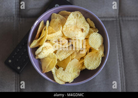 Chip e lontana dalla TV su un divano, dal di sopra Foto Stock