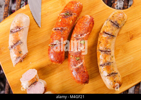 Close up di salsicce alla griglia sul tagliere di legno, barbecue nel giardino. Salsicce bavaresi Foto Stock