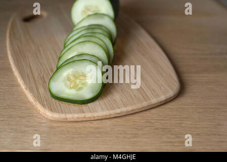 Fette di cetriolo su un bambù tagliere pronto a mangiare Foto Stock