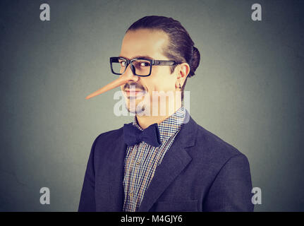 Uomo d affari con il naso lungo isolato su sfondo grigio. Concetto bugiardo. Le emozioni umane, sentimenti. Foto Stock