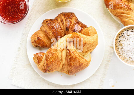 La prima colazione continentale con croissant, confettura di lamponi, caffè. Vista superiore, laici piatta Foto Stock