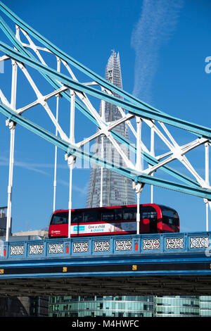 Red London bus attraversando il Tower Bridge con il Coccio in background, London, England, Regno Unito Foto Stock
