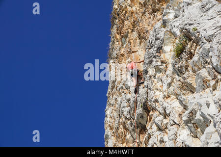 Napoli , Italia -04 settembre 2017 : Un non ben identificato e atletico donna si arrampica su una montagna vicino al mare in una calda giornata estiva .scalare la parete di roccia è una disciplina sportiva praticata da molte persone Foto Stock