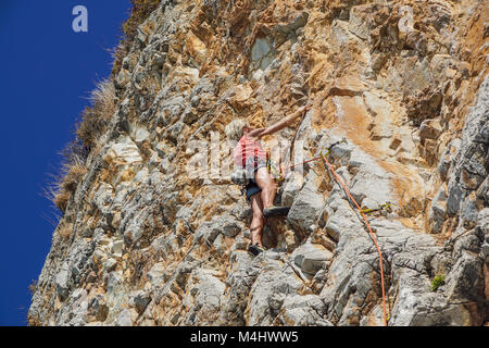 Napoli , Italia -04 settembre 2017 : Un non ben identificato e atletico donna si arrampica su una montagna vicino al mare in una calda giornata estiva .scalare la parete di roccia è una disciplina sportiva praticata da molte persone Foto Stock