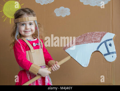 Ritratto di un bambino giocoso con una tuta di cartone su stick cavallo. in stile vintage. Foto Stock