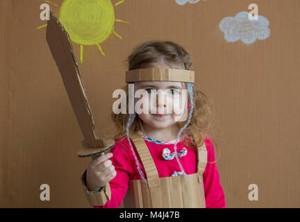 Ritratto di un bambino giocoso con una spada di cartone e un abito stile vintage Foto Stock