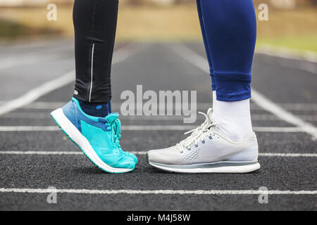 Tagliate il colpo di un maschio e femmina di gambe in scarpe da corsa in piedi vicino all'altra. Amore Concetto di immagine. Foto Stock