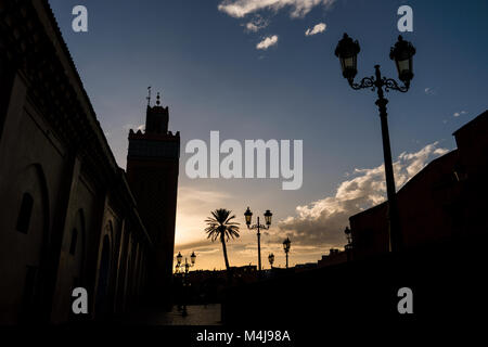 Silhouette di palme e candelabri street lights durante il tramonto a Marrakech, Marocco Foto Stock