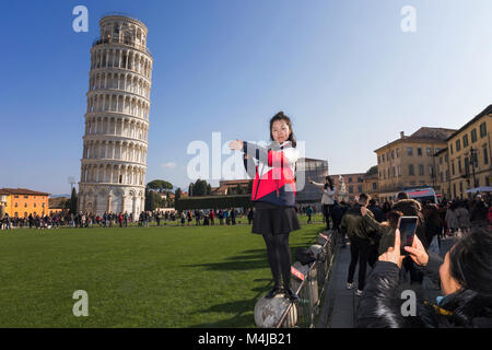 Pisa, Italia - 11 Febbraio 2018: Ragazza asiatica in posa per una foto con la famosa Torre di Pisa in background, in Piazza dei Miracoli affollato con t Foto Stock