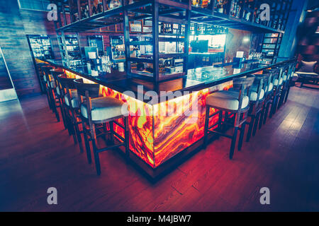 Il bar contemporaneo contatore con le attrezzature e le comode sedie per bar nel ristorante moderno. Elegante arredamento interno. Il blu scuro e rosso c Foto Stock