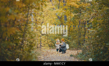 Piuttosto piccola figlia con la sua mamma passeggiate nel parco di autunno - abbraccia Foto Stock