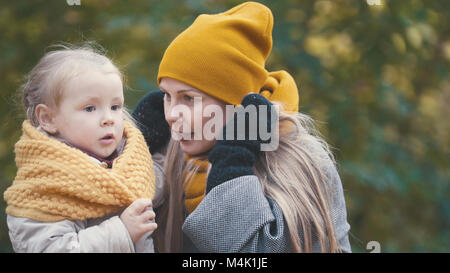 Piuttosto piccola figlia con la sua mamma passeggiate nel parco di autunno Foto Stock