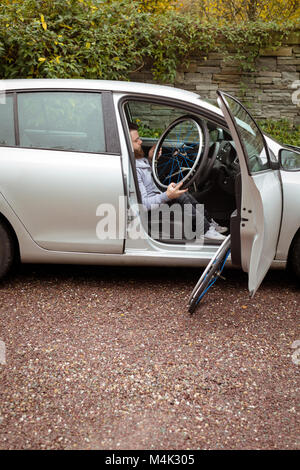 Uomo disabili su sedia a rotelle di contenimento mentre l'imbarco nella sua auto Foto Stock