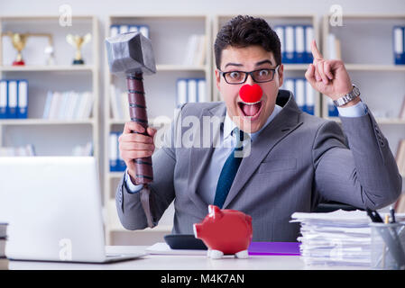 Clown imprenditore con un salvadanaio e un martello Foto Stock
