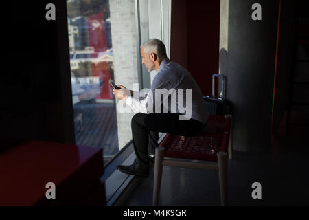 Imprenditore utilizzando il telefono cellulare nella camera di albergo Foto Stock