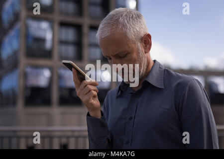 Imprenditore tenendo il telefono cellulare Foto Stock