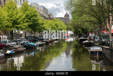 Tipico canale scena in Amsterdam, con barche allineate su entrambi i lati. Un bel riflesso nell'acqua. Le strade di quartiere eseguito su entrambi i lati come bene. Foto Stock