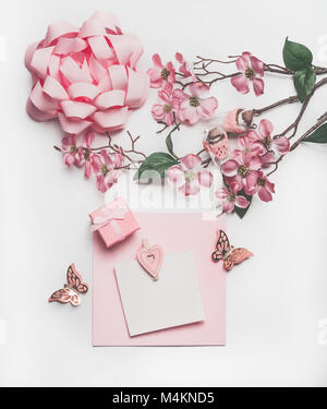 Bella rosa pastello greeting card mock up con il fiore decorazione, cuori, poco confezione regalo e una prua bianco su sfondo scrivania, vista dall'alto, piatto laici. Weddin Foto Stock