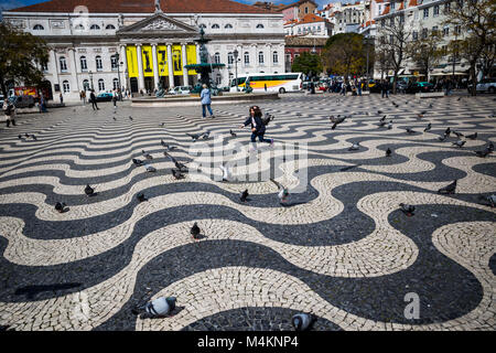 Una giovane ragazza insegue uccelli in Praça Dom Pedro IV, Lisbona, Portogallo. Foto Stock