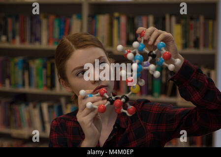 Giovane donna analizzando una molecola modello Foto Stock