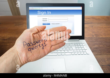 Persona mano mostra una password a portata di mano nella parte anteriore del computer portatile con schermo di login Foto Stock