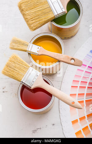 Barattoli di vernice tavolozza di colori, lattine aperto con spazzole sul pannello bianco. Foto Stock
