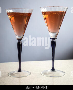 Due bicchieri, viola steli con champagne rosa su sfondo chiaro Foto Stock