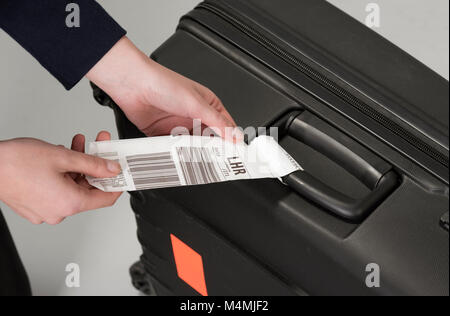 Compagnia aerea bagagli tag di sicurezza essendo attaccato ad un viaggiatori valigia nero Foto Stock