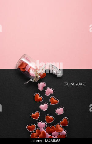 Creative valentines concetto foto della bottiglia con cuori rosa su sfondo nero. Foto Stock